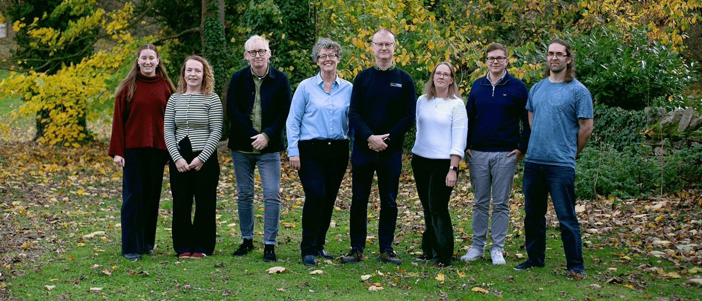 EDC team stood on the grass with leafy trees behind